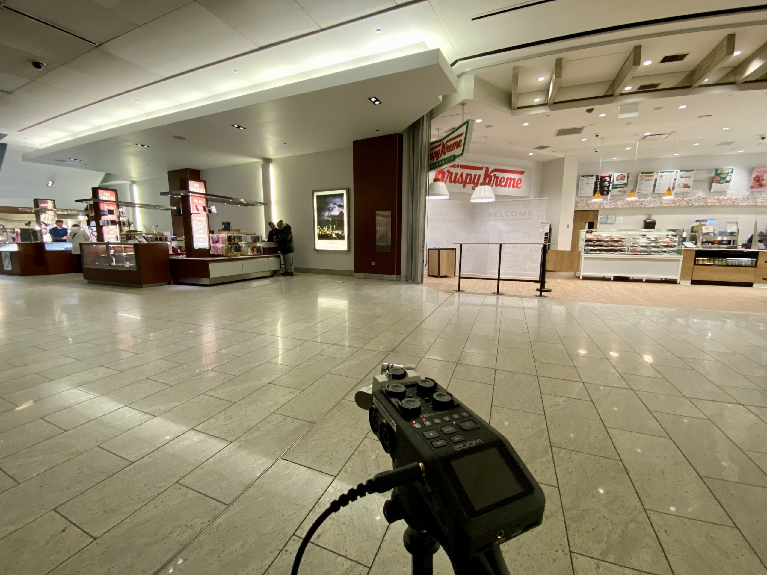 A zoom H6 at end of hallway pointed at kiosks and Krispy Kreme donut shop.