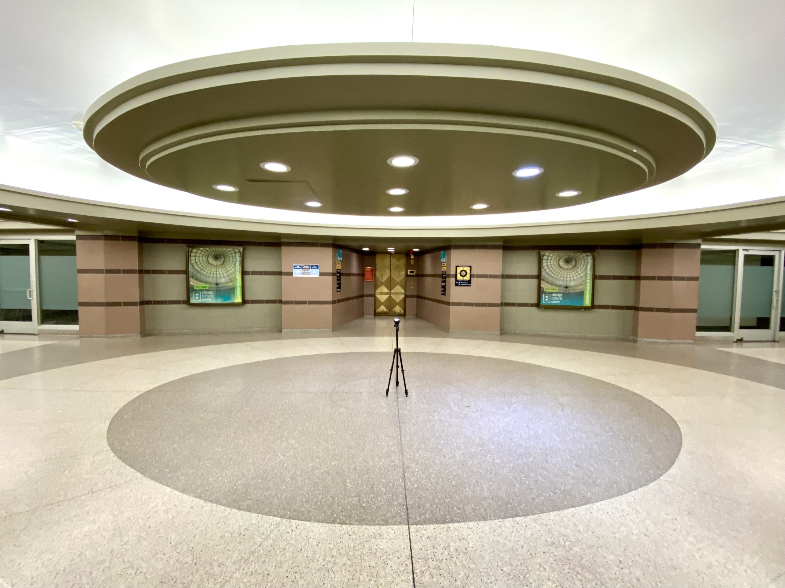 Pedway elevator entrance to the Chicago Cultural Center Image description: In the center of the hallway on the floor is a circular medallion that mirrors the circular lighting that holds recessed lights mirroring the circularity of the famed Tiffany Dome located above and inside the Chicago Cultural Center.